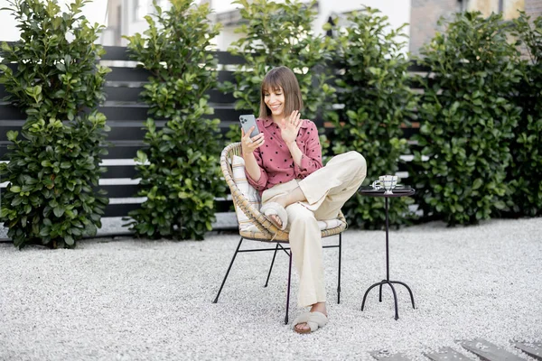 Arka bahçede telefon görüşmesi yapan bir kadın var.