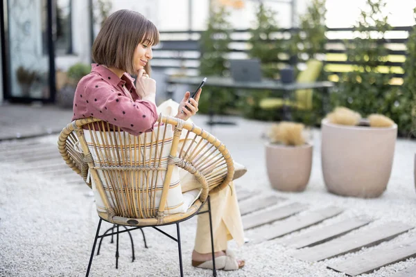 Mujer con teléfono en el patio trasero de su casa — Foto de Stock