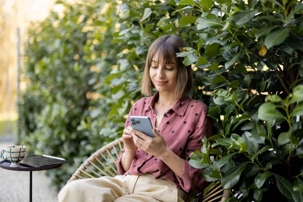 Femme heureuse avec téléphone intelligent sur fond naturel à l'extérieur — Photo