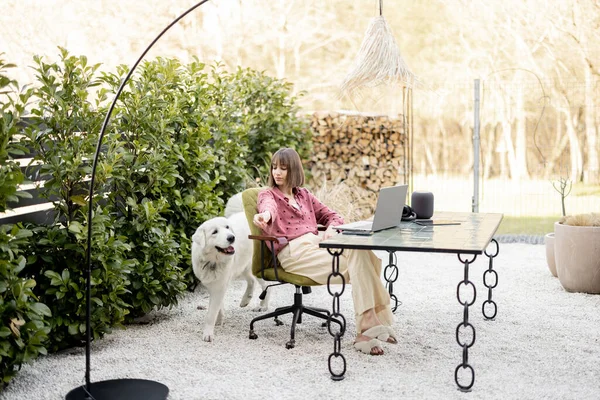 Женщина заботится о своей собаке во время работы на открытом воздухе в уютном саду — стоковое фото