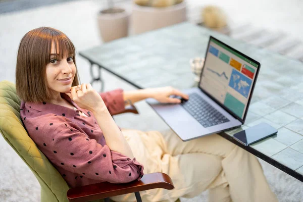 Žena pracuje na notebooku, zatímco sedí u stolu venku — Stock fotografie