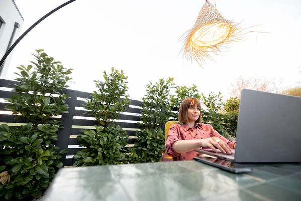 Kadın açık havada internette dizüstü bilgisayarda çalışıyor.