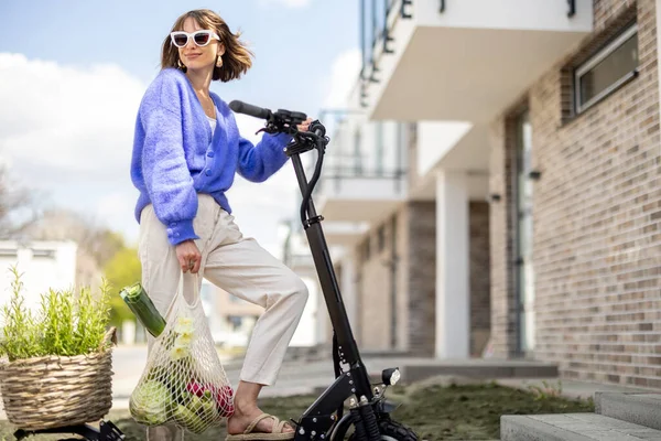 Woman going home with fresh vegetables on electrical scooter — Stockfoto