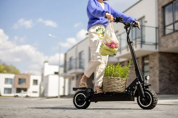 Woman going home with fresh vegetables on electrical scooter — Stok fotoğraf