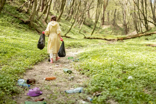 Doğaya saçılmış plastik çöpleri toplayan kişi