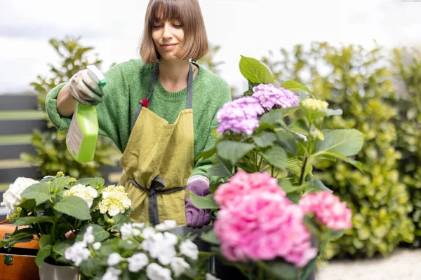 Молода жінка доглядає за квітами в саду — стокове фото