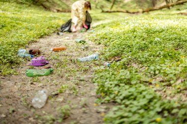 Doğaya saçılmış plastik çöpleri toplayan kişi