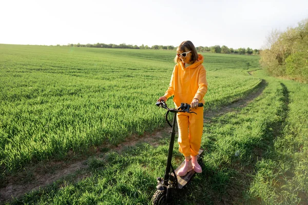 Person rides electric scooter on green field — Stok fotoğraf