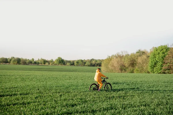 Woman rides a bicycle on a field — Stockfoto