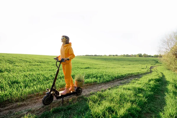 Person rides electric scooter on green field — Stock fotografie