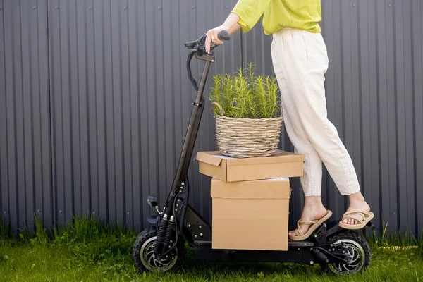 Woman delivering goods by electric scooter — Zdjęcie stockowe