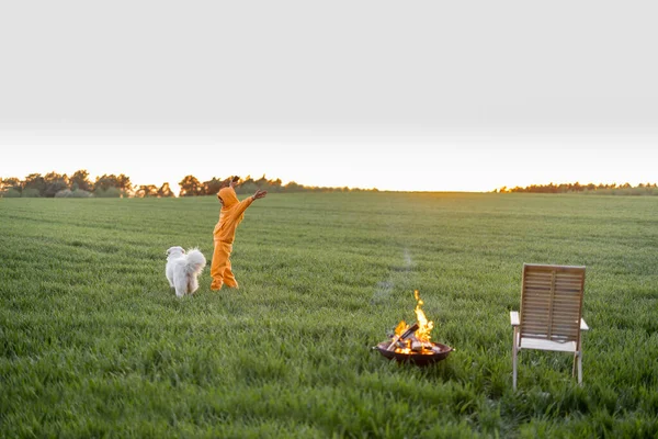 Young person playing with dog on green field by the fireplace — Stok fotoğraf
