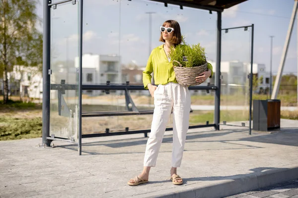 Woman with flowerpot on a bus stop —  Fotos de Stock