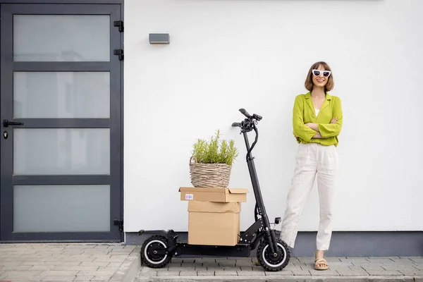 Karton kutular ve saksıyla scooter 'ın yanında duran kadın. — Stok fotoğraf