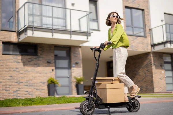 Frau fährt Elektroroller mit Pappverpackungen — Stockfoto