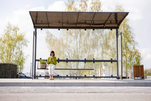 Mujer con maceta en parada de autobús moderna — Foto de Stock