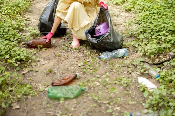 Mujer recogiendo basura plástica dispersa en el bosque —  Fotos de Stock