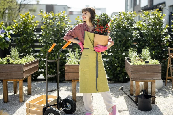 Bahçede çiçekli yeşil önlüklü bahçıvanın portresi.