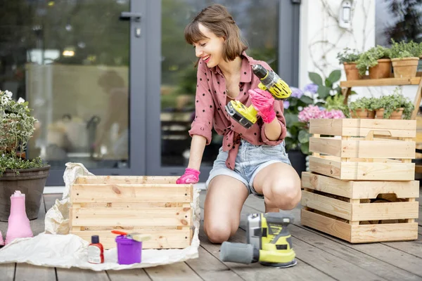 Housewife repairs wooden boxes on terrace — Photo