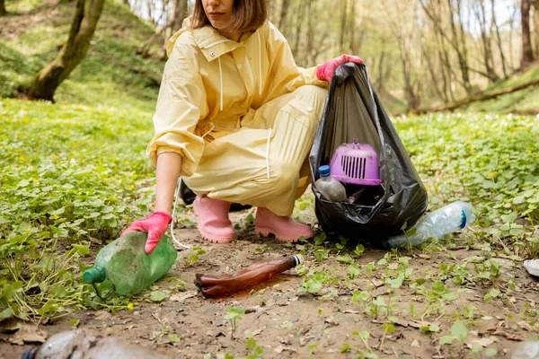 森の中に散在するプラスチックごみを集める女性 — ストック写真