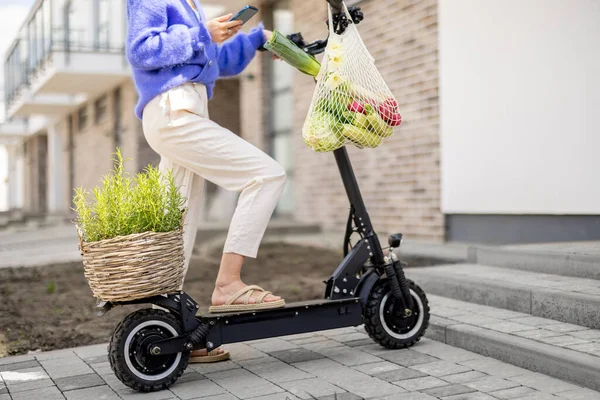 Kadın elektrikli scooter kullanıyor. Ağlı çanta dolusu sebzeyle. Yakın plan. — Stok fotoğraf