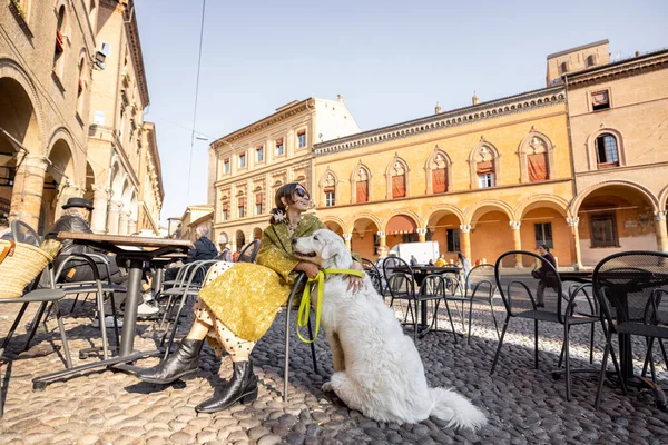 Donna seduta con il suo cane bianco al caffè all'aperto nel centro storico di Bologna — Foto Stock