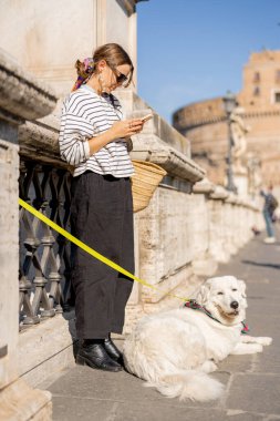 Beyaz köpekli bir kadın Roma 'da sokakta oturuyor.