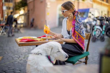 Roma 'da bir restoranda köpekle otururken İtalyan makarnası yiyen bir kadın.