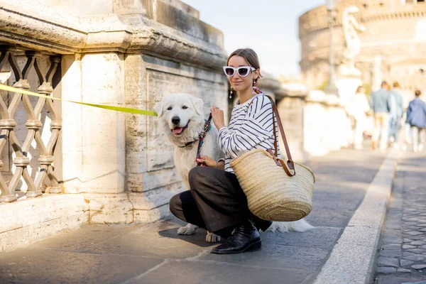 Beyaz köpekli bir kadın Roma 'da sokakta oturuyor.