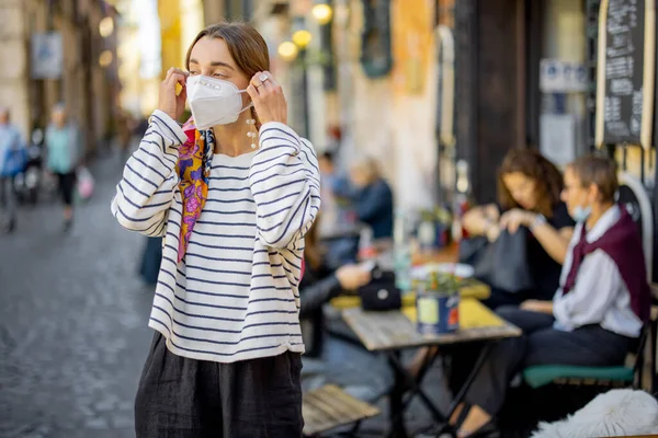 Woman takes off face mask while walking on the crowded street — Stock Photo, Image