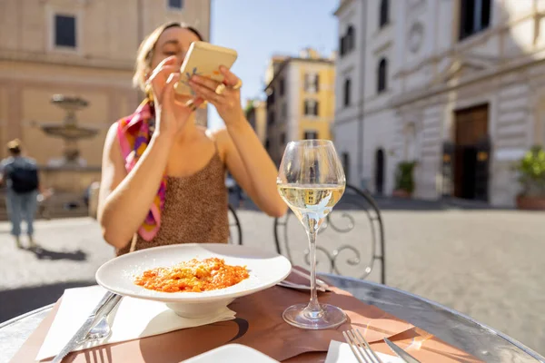 Mulher tira foto de macarrão italiano no restaurante na rua em Roma — Fotografia de Stock