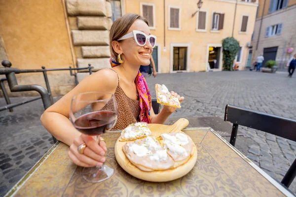 Egy nő pizzát eszik egy olasz étteremben a szabadban — Stock Fotó