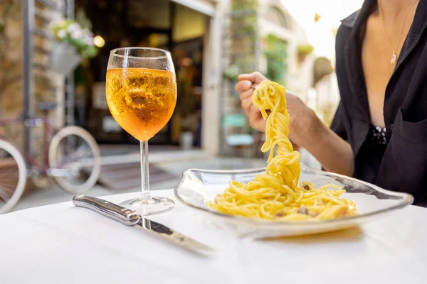 Kobieta je lunch z makaronem i winem w przytulnej włoskiej restauracji na świeżym powietrzu. — Zdjęcie stockowe