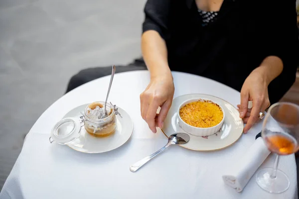 Vrouw eet dessert met crème brulee in het restaurant buiten — Stockfoto