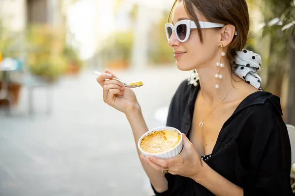 Женщина ест десерт с крем-брюле в ресторане на открытом воздухе — стоковое фото