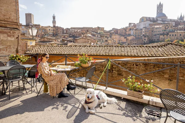 Giovane donna a pranzo, seduta con un cane al ristorante all'aperto della città di Siena — Foto Stock