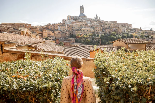 Donna cammina sullo sfondo del paesaggio urbano del centro storico di Siena in Italia — Foto Stock