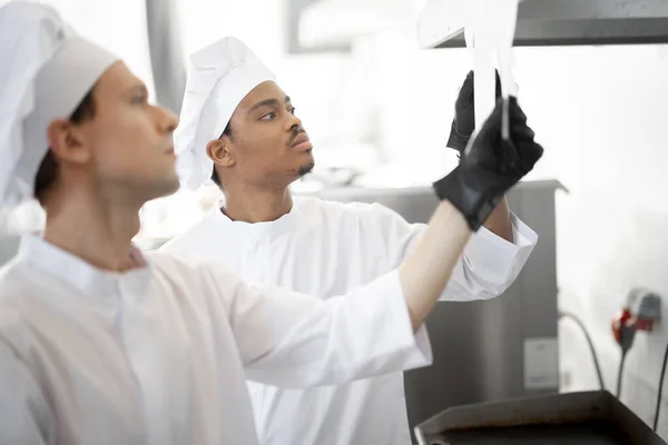 Chefs olhar em cheques impressos com pedidos enquanto cozinha na cozinha profissional — Fotografia de Stock