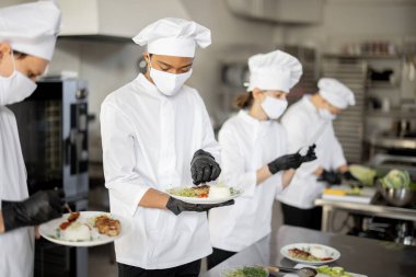 Mutfaktaki bir restoran için hazır yemeklerle bekleyen çok ırklı aşçılar.
