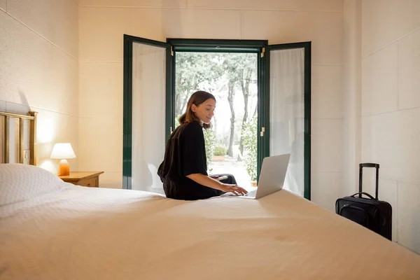 Bir Kadın Otel Odasında Yatıp Akıllı Telefon Dizüstü Bilgisayar Kullanıyor — Stok fotoğraf