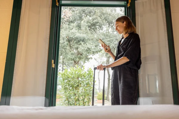 Vrouw Met Telefoon Bagage Buurt Van Raam Oude Stijl Hotelkamer — Stockfoto