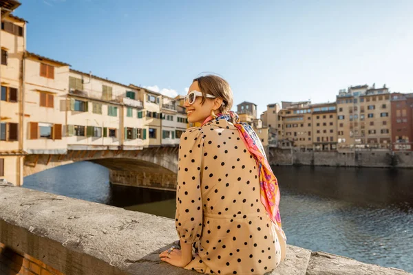 年轻女子在佛罗伦萨著名的老桥上欣赏美丽的风景 日落时坐在河边 参观意大利地标的女性游客 穿着衣服和五颜六色的披肩的时髦女人 — 图库照片