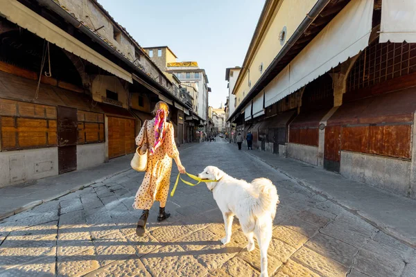 有名な古い橋の上に犬と一緒に歩く女性 ポンテ ヴェッキオと呼ばれます フィレンツェで 旅行イタリアのランドマークの概念 カラフルなショールやサングラスを持つスタイリッシュな女性 — ストック写真