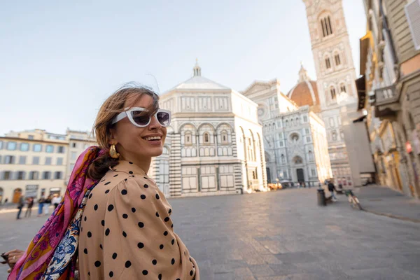 Woman enjoys beautiful view on famous Duomo cathedral in Florence, standing on empty cathedral square during morning time. Stylish woman visiting italian landmarks. Traveling Italy concept