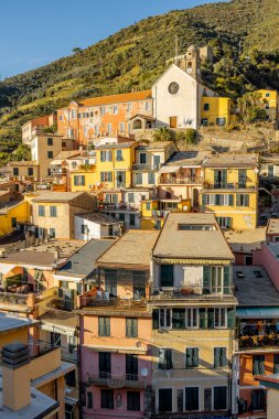 Güneşli bir günde tepede renkli eski evleri ve kilisesi olan Vernazza köyünün manzarası. İtalya 'nın kuzeybatısındaki Cinque Terre Ulusal Parkı' nda ünlü bir köy.