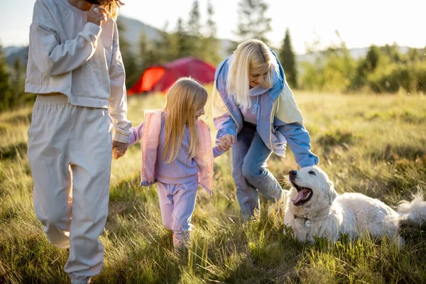两个女人带着小女孩和白狗散步 快乐地在大自然中度过夏天 有小孩的同性恋家庭在山上旅行 — 图库照片