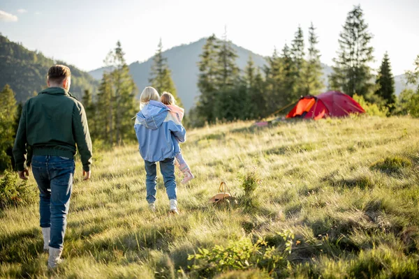 日落时分 年轻的高加索家庭带着小女孩与帐篷一起在绿茵的草地上散步 在营地度过暑假的快乐家庭 — 图库照片