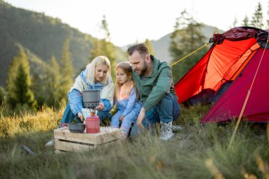 Küçük kızı olan bir çift, dağlarda çadır kurup seyahat ederken kamp alanında piknik yapıyor. Genç aile tatillerini mutlu bir şekilde doğada geçiriyor.
