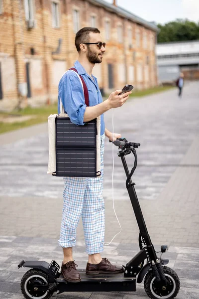 Stilvoller Typ Fährt Elektroroller Und Lädt Handy Mit Solarzelle Unterwegs — Stockfoto