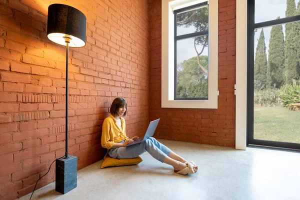 Young Woman Works Laptop Computer While Sitting Relaxed Room Brick — стоковое фото